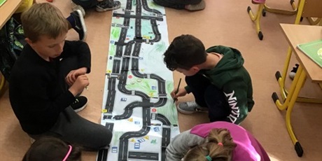 Powiększ grafikę: Uczniowie kolorują makietę ulicy i przyklejają znaki drogowe.