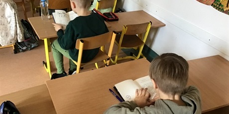 Powiększ grafikę: Uczniowie w sali czytają cicho książki.