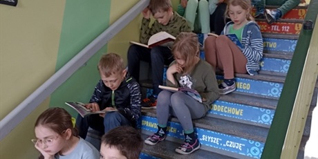 Powiększ grafikę: Klasa druga czyta na schodach.