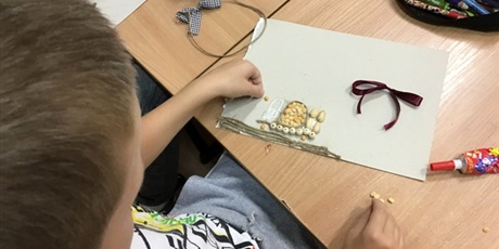 Powiększ grafikę: Uczeń wykleja drewnianymi koralikami.