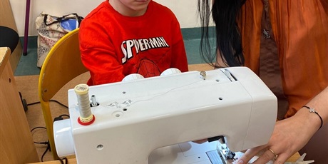 Powiększ grafikę: Uczeń obserwuje szycie na maszynie.