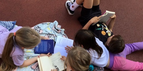 Powiększ grafikę: Grupa dziewczynek wspólnie czyta.