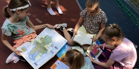 Powiększ grafikę: Grupa dziewczynek czyta książki.