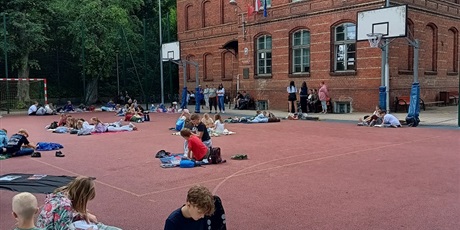 Powiększ grafikę: Budynek szkolny i czytający uczniowie.