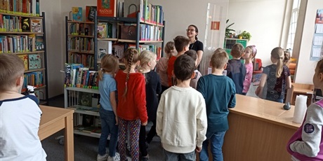 Powiększ grafikę: Uczniowie słuchają opowiadania bibliotekarza.